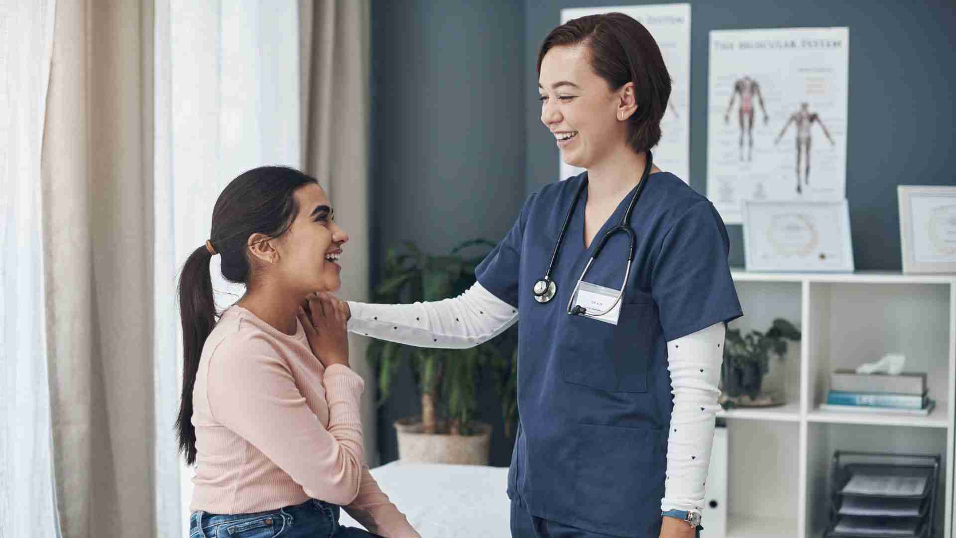 Registered nurse in scrubs consulting smiling patient in clinical setting.